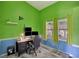 A home office featuring bright green and blue walls, multiple monitors, and natural light from the windows at 2816 Manor Hill Dr, Brandon, FL 33511