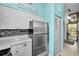 Well-lit kitchen features stainless steel refrigerator, tile backsplash, white cabinets and doorway to the outside at 300 S Florida Ave # 200J, Tarpon Springs, FL 34689