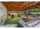 A covered backyard patio setup, with lounge furniture, pond, and neatly maintained lawn at 308 Jeanal Pl, Tampa, FL 33612