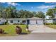 Charming single-story home with a well-manicured lawn, blue door, and a two-car garage under a clear blue sky at 308 Jeanal Pl, Tampa, FL 33612