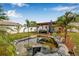 Backyard pond with rock border, landscaped edge, pergola with furniture, and tropical plants at 308 Jeanal Pl, Tampa, FL 33612