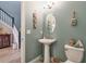 Stylish powder room with pedestal sink, oval mirror, and coastal-themed decor at 3122 Christophers Watch Ln, Ruskin, FL 33570