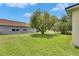 Lush backyard with well-kept lawn, mature trees, and the house exterior with large windows allowing natural light at 3333 Michener Pl, Plant City, FL 33566