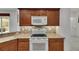Well-equipped kitchen featuring wood cabinets, modern white appliances, and stylish tiled backsplash at 3333 Michener Pl, Plant City, FL 33566
