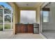 Outdoor kitchen featuring wooden cabinets, a sink, and a mini-refrigerator on screened in patio at 3333 Michener Pl, Plant City, FL 33566
