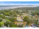 An aerial view displays a neighborhood near a body of water, surrounded by verdant trees and under a clear sky at 3417 1St W Ave, Bradenton, FL 34205