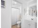 This bathroom includes a tile floor, white shower curtain, white vanity, and an illuminated mirror at 3417 1St W Ave, Bradenton, FL 34205