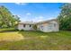 View of the rear exterior of the single-story home with a small porch and lush greenery at 3417 1St W Ave, Bradenton, FL 34205