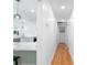 Bright hallway with hardwood floors leading to a kitchen with white cabinets and pendant lighting at 3417 1St W Ave, Bradenton, FL 34205
