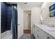 Bathroom featuring a blue tiled shower, white vanity with a granite countertop, and modern decor at 4009 Carrollwood Village Dr, Tampa, FL 33618