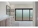 Well-lit bathroom with double vanity, decorative mirror, and sliding doors leading to outdoor space at 4009 Carrollwood Village Dr, Tampa, FL 33618