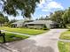 A one-story home with mature landscaping, and a long driveway for ample parking at 4009 Carrollwood Village Dr, Tampa, FL 33618