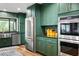 Modern kitchen with stainless steel appliances, green cabinets, and wood floors at 4009 Carrollwood Village Dr, Tampa, FL 33618