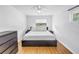 A simple bedroom featuring a white bed, bedside tables, and light wood floors at 4432 W Mccoy St, Tampa, FL 33616