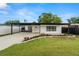 Charming single-story home featuring a covered parking area, a fresh green lawn, and beautifully manicured landscaping at 4681 70Th N Ave, Pinellas Park, FL 33781