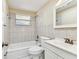 Bathroom featuring tiled walls, white fixtures, a bathtub, and a window for natural light at 5033 Tammy Ln, Holiday, FL 34690
