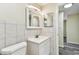 Bathroom featuring tiled walls, a white vanity, mirrors, and a toilet at 5033 Tammy Ln, Holiday, FL 34690