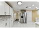 Bright kitchen featuring white cabinets, stainless steel appliances, and stone backsplash at 5033 Tammy Ln, Holiday, FL 34690