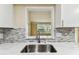Bright kitchen boasts a stainless steel sink, white cabinets, and modern backsplash at 5033 Tammy Ln, Holiday, FL 34690
