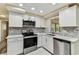 Well-lit kitchen features white cabinets, stainless steel appliances, and stylish mosaic backsplash at 5033 Tammy Ln, Holiday, FL 34690