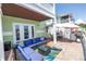 A covered brick patio with a blue outdoor sofa and outdoor table with umbrella at 5037 Starfish Se Dr # A, St Petersburg, FL 33705