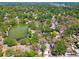 An aerial view shows a neighborhood with tree-lined streets surrounding a pond and lush greenery at 5806 N 9Th St, Tampa, FL 33604