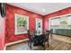 Dining area features rustic hardwood floors, textured red walls, and an adjacent kitchen with modern appliances at 5806 N 9Th St, Tampa, FL 33604