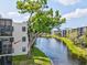 Condo building overlooking a tranquil lake, surrounded by lush greenery and mature trees under a bright, sunny sky at 5980 Terrace Park N Dr # 214, St Petersburg, FL 33709