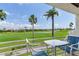 Balcony with table and chairs overlooking a lush golf course with palm trees and water feature at 6171 Bahia Del Mar Blvd # 216, St Petersburg, FL 33715