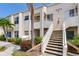 Beige condo exterior with white stairs, balcony, and lush landscaping at 6171 Bahia Del Mar Blvd # 216, St Petersburg, FL 33715