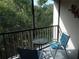 View of the exterior trees from the covered balcony with outdoor furniture and colorful lizard art at 860 Virginia St # 308, Dunedin, FL 34698