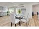 Sunlit dining area features a round table with gray upholstered chairs, a decorative plant centerpiece, and an abstract art piece at 1114 Michigan N Dr, Dunedin, FL 34698