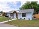 Charming single-story home with blue stucco exterior, decorative wooden accents, and well-manicured lawn at 1114 Michigan N Dr, Dunedin, FL 34698