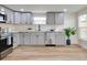 Well-lit kitchen features sleek gray cabinetry, stainless steel appliances, modern fixtures, and wood-look flooring at 1114 Michigan N Dr, Dunedin, FL 34698