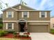 Two-story home featuring neutral stucco, white trim, shuttered windows, a two car garage, and a landscaped front yard at 12607 Flatwood Creek Dr, Gibsonton, FL 33534