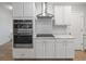 Modern kitchen with stainless steel appliances, stylish range hood, and tile backsplash at 12607 Flatwood Creek Dr, Gibsonton, FL 33534