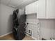 This cozy laundry space features a stackable washer and dryer, with overhead cabinets and hanging rack, maximizing efficiency at 12607 Flatwood Creek Dr, Gibsonton, FL 33534