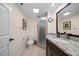Well lit bathroom featuring a granite vanity top, framed mirror, glass shower, and neutral toned tiles at 12900 Vonn Rd # F101, Largo, FL 33774
