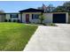 Charming one story home with large front yard, colorful door, dark shutters and an American flag at 12907 College Hill Dr, Hudson, FL 34667