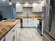 Modern kitchen with white cabinetry, butcher block countertops, stainless steel appliances, and subway tile backsplash at 12907 College Hill Dr, Hudson, FL 34667