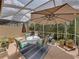 Outdoor lanai with comfortable seating, large umbrella, and view of garden at 13209 Palmilla Cir, Dade City, FL 33525