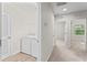 The laundry room is shown with a washer and dryer, shelving, a door to the outside, and a hallway at 13233 Canopy Creek Dr, Tampa, FL 33625