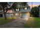 Two-story home with white and yellow siding, green shutters, attached garage, and mature trees in the front yard at 1810 Maryland Ne Ave, St Petersburg, FL 33703