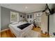 Well-lit bedroom featuring hardwood floors, gray walls, two windows, and a white comforter with a black blanket at 18198 3Rd E St, Redington Shores, FL 33708