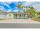 Inviting single-story home features a vibrant exterior, a well-kept lawn, and mature palm trees at 18198 3Rd E St, Redington Shores, FL 33708