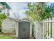 Backyard storage shed surrounded by manicured greenery and a classic white picket fence at 18198 3Rd E St, Redington Shores, FL 33708