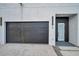 Close-up of a modern garage with dark door, complemented by a sleek entry and landscaped surroundings at 2608 W Columbus Dr # 1, Tampa, FL 33607