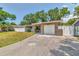 Charming exterior view of home, featuring a long driveway, lush lawn, and an attached single-car garage at 2933 Stratford Dr, Largo, FL 33771
