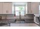 Granite countertops accent stainless steel sink by window, and white cabinets in renovated kitchen at 3300 58Th N St, St Petersburg, FL 33710