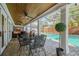 Relaxing covered patio featuring brick pavers, ceiling fans, and a dining area near the sparkling screened-in pool at 3304 Latania Dr, Tampa, FL 33618